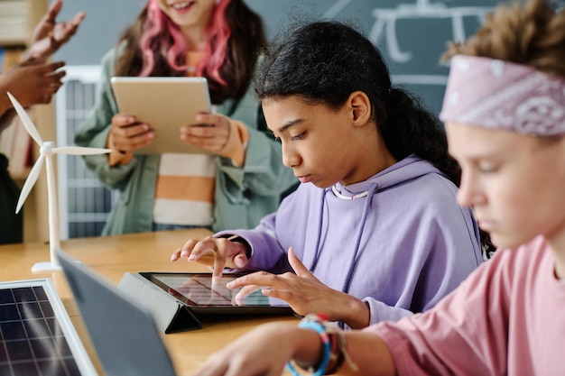 Foto colegiala usando aparatos durante la lección junto con sus compañeros de clase