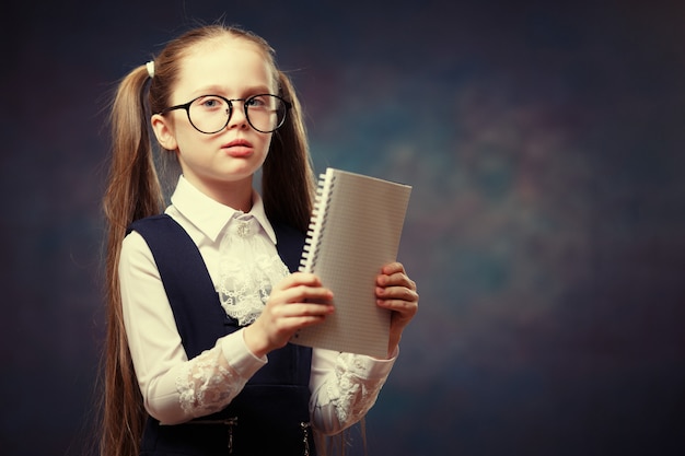 Colegiala Use gafas Uniforme Mira el cuaderno. Tono de color