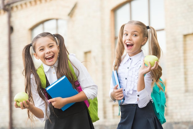 Colegialas alegres que disfrutan del concepto del día del conocimiento del almuerzo escolar saludable