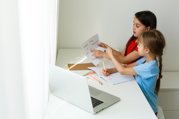 Colegialas bastante elegantes que estudian matemáticas durante su lección en línea en casa, distancia social durante la cuarentena, autoaislamiento, concepto de educación en línea