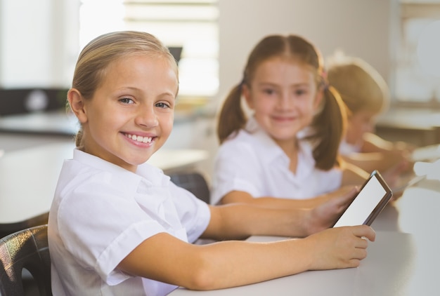 Colegialas con tableta digital en el aula