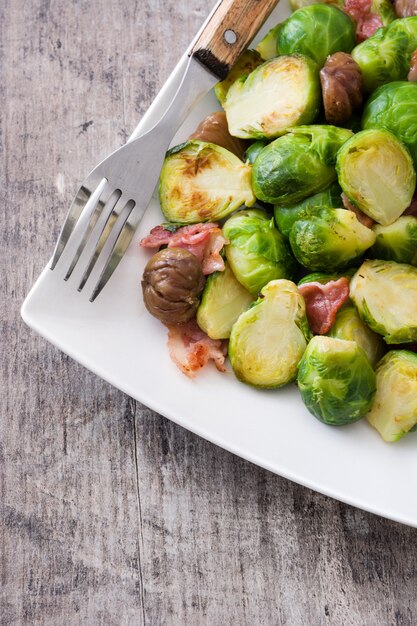 Coles de Bruselas con castañas y tocino en mesa de madera