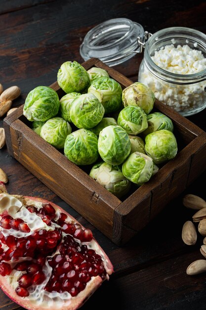 Coles de Bruselas, con granada, requesón y pistachos, sobre mesa de madera antigua