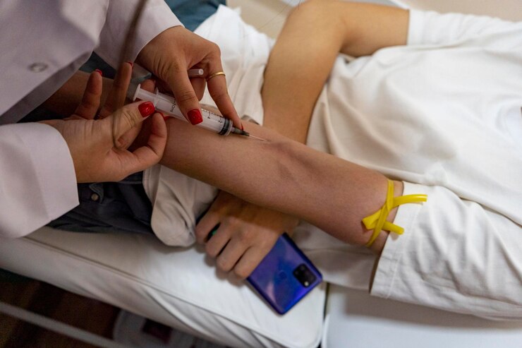 Foto coletando amostra de sangue de uma paciente médica com esmalte vermelhoseringa de 10mlinjeção intravenosa perto da fossa cubital
