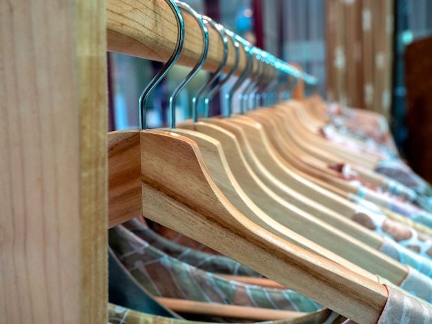 Colgadores de ropa de madera con camisas coloridas colgadas en un estante de tela de madera en una tienda de moda de estilo asiático