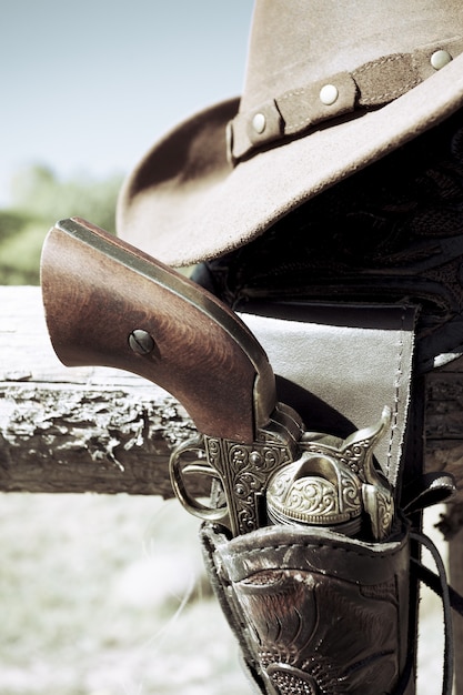 Colheita de arma de cowboy e chapéu ao ar livre sob a luz do sol