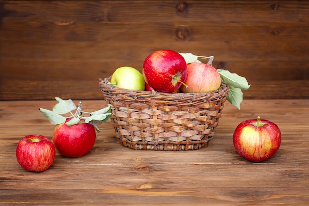Colheita de maçãs. Maçãs vermelhas em uma cesta de vime em uma mesa de madeira velha