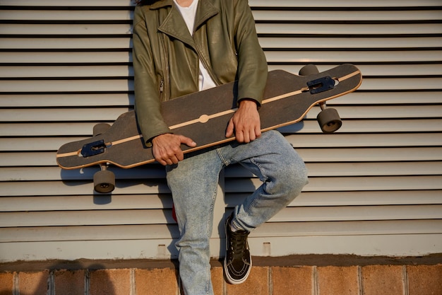 Colheita de skater urbano homem posando para a câmera com longboard