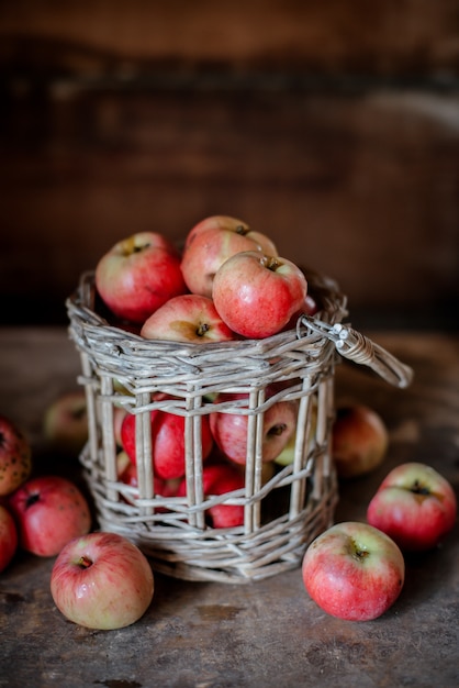 Colheita fresca de maçãs maduras e saudáveis da fazenda em uma jarra de vidro, em uma cesta.