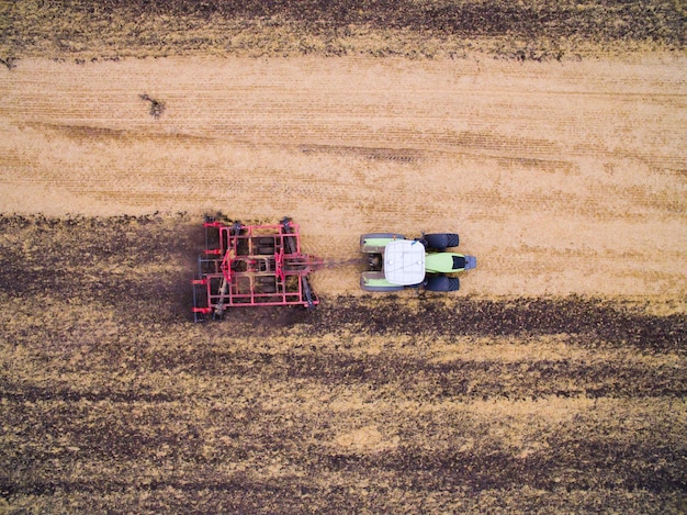 Colheita no campo. Vista aérea. Cultivo da terra com um trator