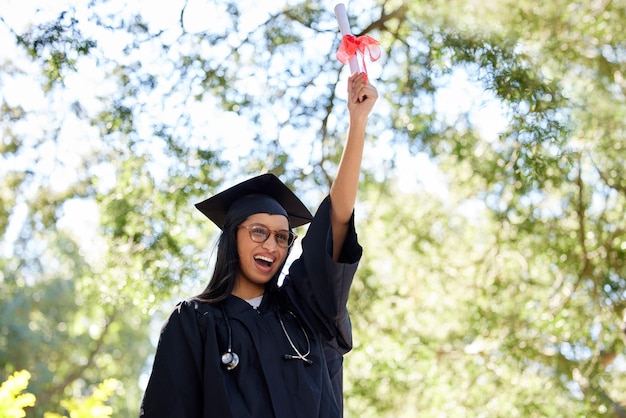 Colhendo as recompensas. Foto recortada de uma jovem atraente posando do lado de fora com seu diploma.