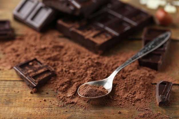 Colher com cacau em pó e chocolate escuro na mesa