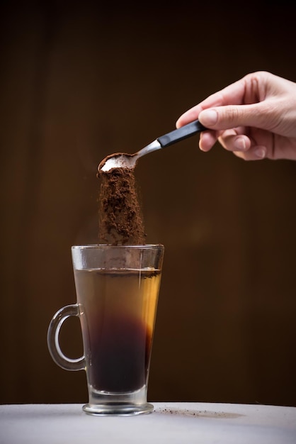 Colher com café em movimento caindo em uma xícara de conceito de café da manhã de chá muito quente