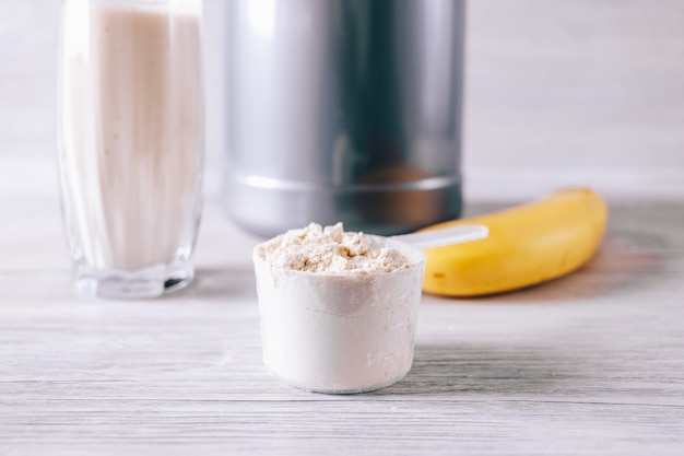 Colher com proteína em pó, banana e vidro