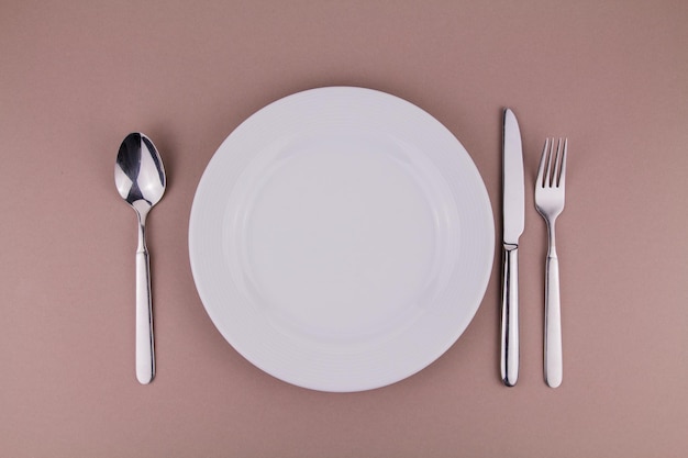 Colher de garfo e faca de prato de configuração de mesa na placa branca de fundo cinza