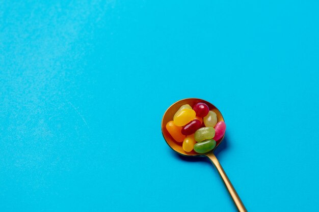 Foto colher de ouro com doces na parede azul