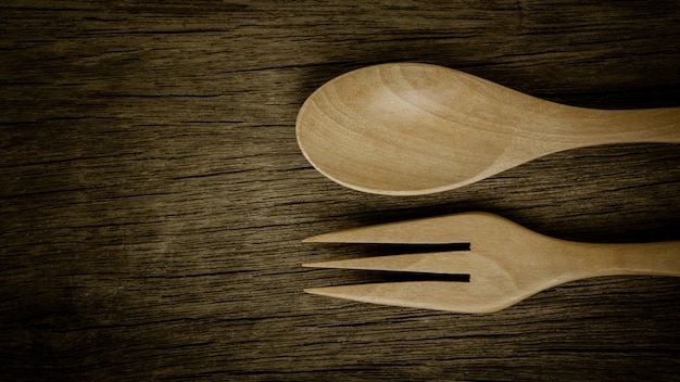 Colher e forquilha de madeira na mesa de madeira velha. - estilo vintage.