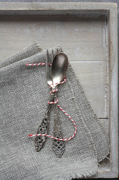 Colher e garfo em guardanapo de pano de saco na bandeja de madeira
