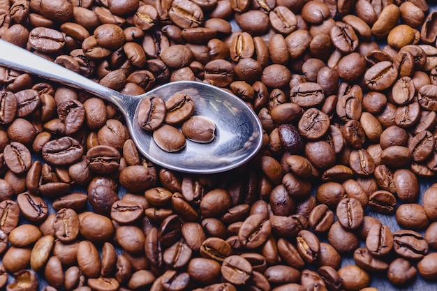 Colher em grãos de café sobre fundo preto de pedra