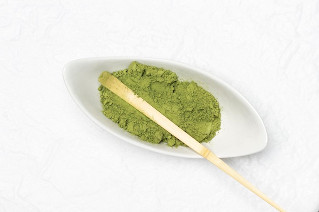 Colher medidora de bambu em uma tigela com matcha em pó