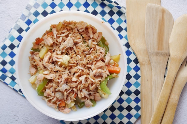 Colher pegar salada de atum de uma tigela na mesa