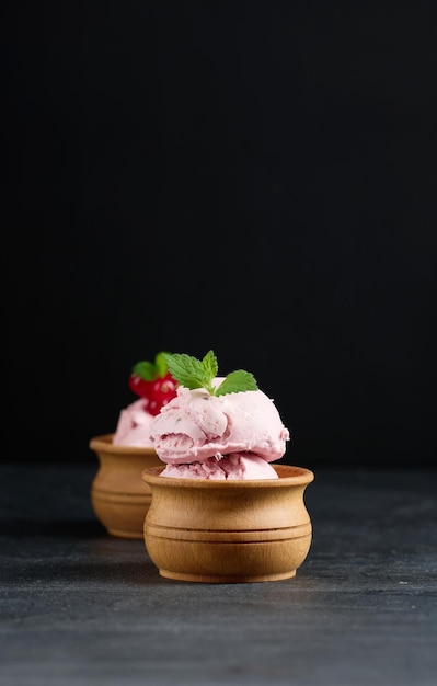 Foto colheres cor-de-rosa de picolés com groselhas em uma mesa preta sorvete