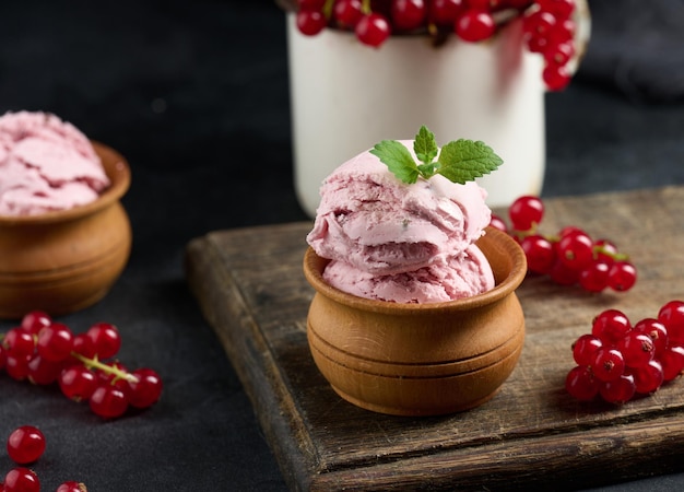 Foto colheres cor-de-rosa de picolés com groselhas em uma mesa preta sorvete