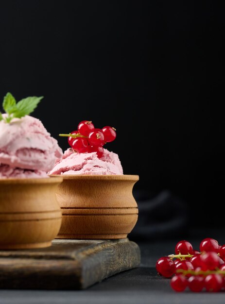 Foto colheres cor-de-rosa de picolés com groselhas em uma mesa preta sorvete