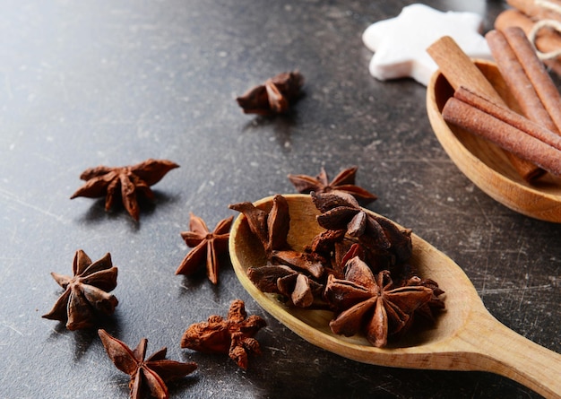 Colheres de madeira com estrelas de anis e canela na mesa escura, vista de perto