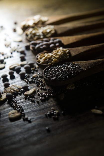 Colheres de pau com cereais e sementes de madeira