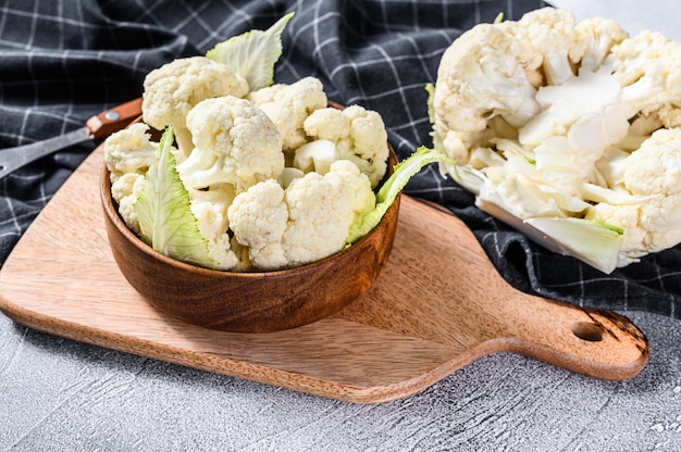 Coliflor cruda cortada en trozos en un tazón de madera