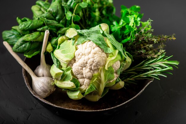 Coliflor entera y varias verduras Comida vegetariana saludable Fondo oscuro