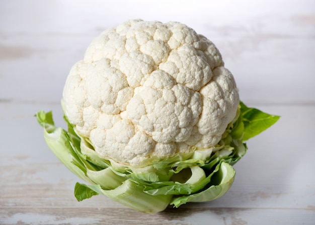 Coliflor en mesa de madera blanca