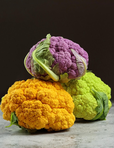 Coliflores de colores frescos sobre fondo oscuro, vista lateral. Comida multicolor. Púrpura, amarillo, verde