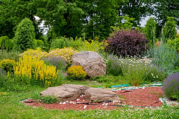 Colina alpina con césped verde y exuberante Césped y camino sinuoso en un hermoso jardín de estilo inglés