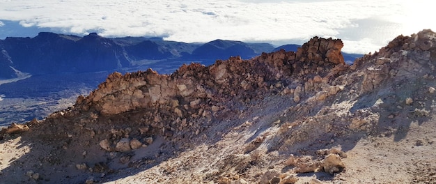 Una colina rocosa con una montaña al fondo.