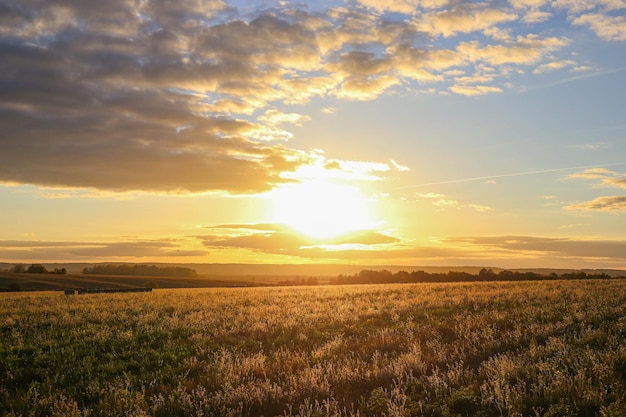 Colinas de campos agrícolas al amanecer o al atardecer en otoño con cielo en las nubes