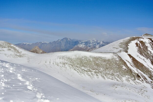 Colinas de montanha levemente cobertas de neve no início da temporada de esqui em Gudauri, Geórgia, vista idílica e tranquila no horizonte