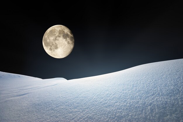 Colinas de nieve y cielo azul profundo a la luz de la luna