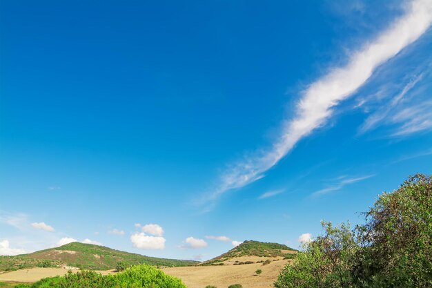 Colinas verdes y cielo azul con nubes en un día soleado en Alghero Cerdeña