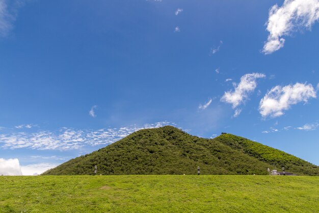 Colinas verdes e cerca grama exuberante, céu azul com nuvens brancas