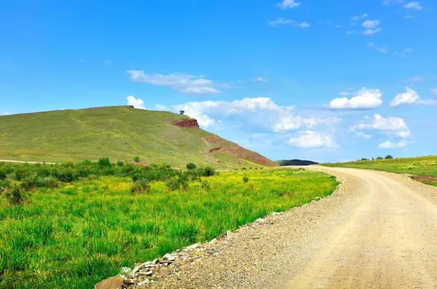 Colinas verdes no verão, sob um céu azul nublado. Sibéria, Rússia