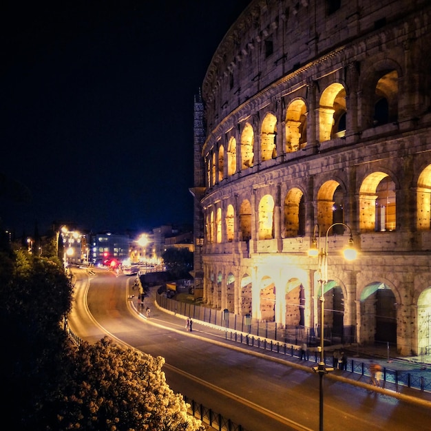 Coliseo iluminado por una carretera vacía en la ciudad por la noche