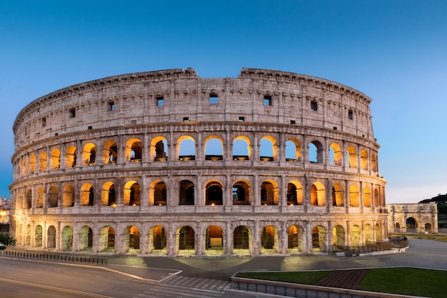 Coliseo iluminado contra el cielo azul claro al anochecer