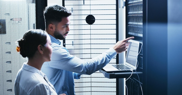 Collaboration laptop and problem solving with people in server room for network administration Computer conversation and cybersecurity with IT support team in data center for troubleshooting