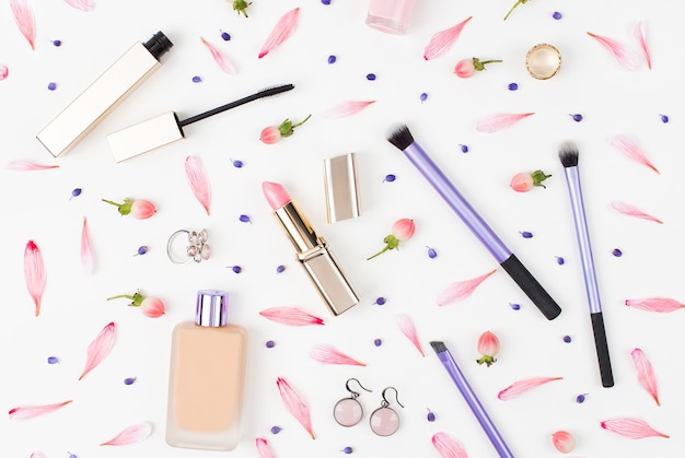 Collage de cosméticos con pincel de lápiz labial y otros accesorios sobre fondo blanco.