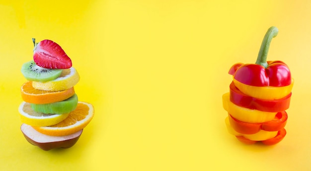 Collage einer Pyramide aus gehacktem Obst und Gemüse im Gleichgewicht auf gelbem Hintergrund Nahaufnahme