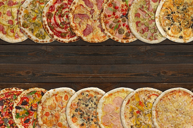 Collage horizontal de diferentes pizzas al horno sobre fondo de madera oscura.