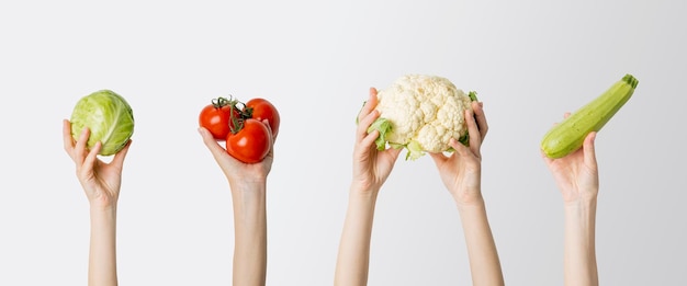 Collage con manos femeninas sosteniendo repollo tomate coliflor calabacín sobre fondo blanco Banner