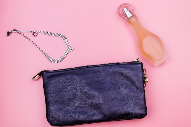 Collar de bolso de embrague y botella de perfume sobre fondo rosa Vista superior Concepto de belleza y moda